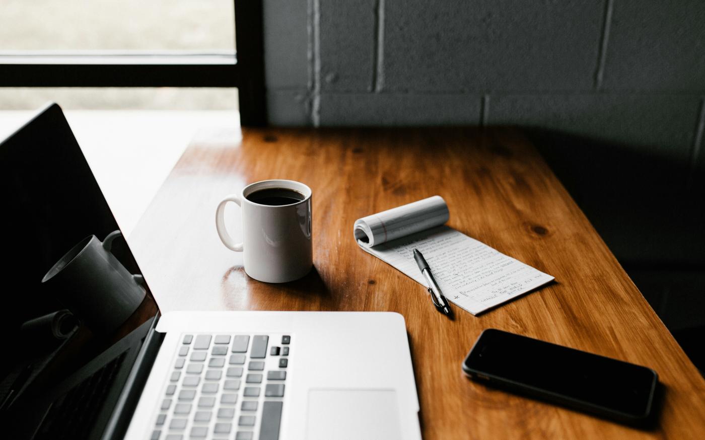 MacBook Pro, white ceramic mug,and black smartphone on table by Andrew Neel courtesy of Unsplash.